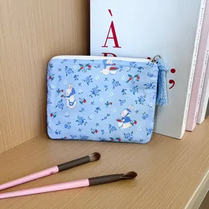 Close-up detail shot of a cute blue floral pattern pouch with a white rabbit illustration and tassel.