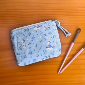 Light blue fabric coin purse with cute bunny and floral print, portable makeup pouch detail.