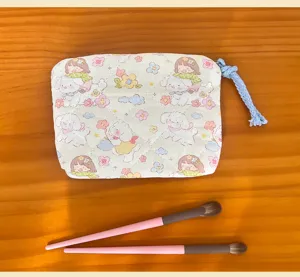 Quilted cartoon cosmetic bag detail view, cute girl and puppy pattern with blue zipper pull.