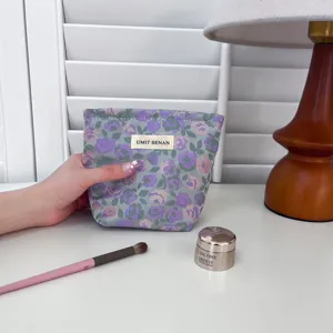 Dettaglio della trousse per cosmetici in tessuto con motivo floreale e design portatile.