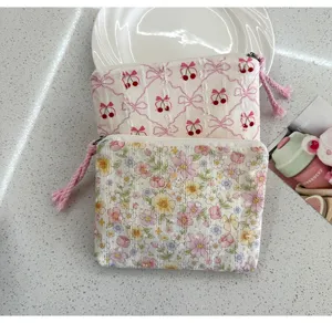 Close-up detail of cute floral and cherry print fabric zipper pouches, portable cosmetic makeup bag.