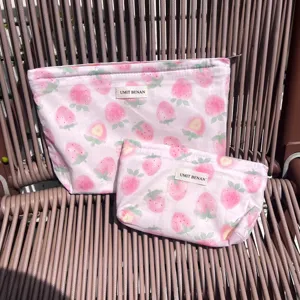 Dettaglio di borsa cosmetica rosa con motivo fragola, mostra due comode belle pochette.