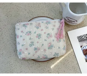 Floral cosmetic bag detail shot, compact portable storage pouch with cute tassel zipper pull.