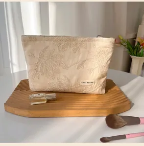 Beige floral embroidered cosmetic bag, portable makeup storage pouch with zipper for travel.