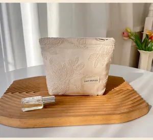 Beige embroidered cosmetic bag with floral pattern and zipper closure for travel storage