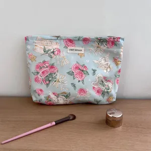 Detailed close-up shot of vintage rose and angel printed cosmetic pouch with woven label.