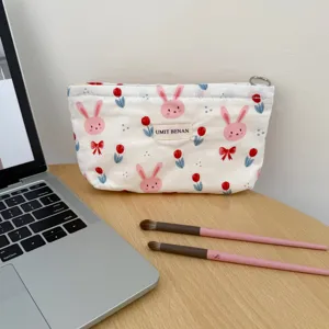 Canvas makeup pouch detail showing cute bunny pattern, zipper closure and woven brand tag.