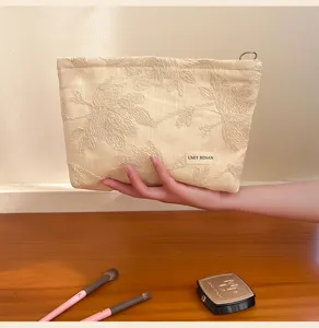 Beige floral embroidered cosmetic bag for travel and daily storage with zipper closure.