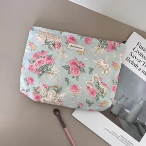 Detailed view of vintage angel and rose pattern cosmetic bag featuring soft fabric and woven label.