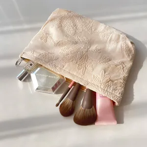 Beige embroidered cosmetic bag for women, portable travel makeup pouch and toiletry organizer.