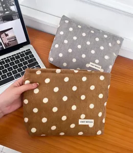 Detailed view of brown and grey corduroy polka dot cosmetic pouch with secure zipper.