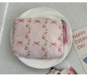 Detailed view of the pink striped floral coin purse, featuring a zipper and braided wrist strap.