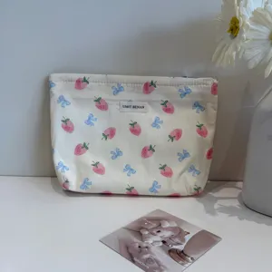 Portable canvas makeup bag with cute strawberry and bow print, ideal for travel and storage.