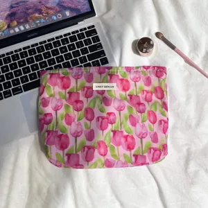 Pink floral tulip print cosmetic pouch detail shot, fabric makeup bag with zipper and woven label.
