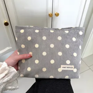 Detailed view of the retro polka dot corduroy cosmetic bag featuring a brand label and soft fabric.
