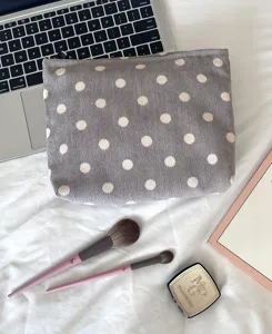 Grey corduroy cosmetic bag with white polka dots, stylish zip travel makeup pouch for women.