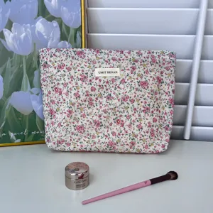 Detail shot of a floral cotton makeup bag with zipper, showcasing fabric and label.