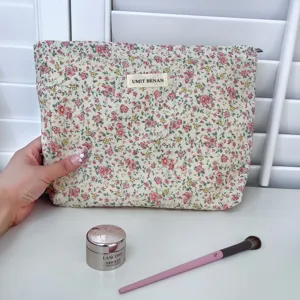 Floral cosmetic bag detail view showing fabric texture, cute pink floral pattern and label.