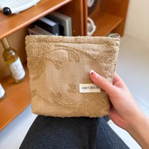 Vintage linen embroidered cosmetic bag, portable floral makeup pouch with stylish brand label.