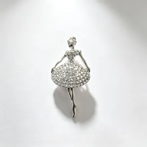 Closeup of sparkling rhinestone ballerina brooch, detailed silver alloy crafting and crystal texture.