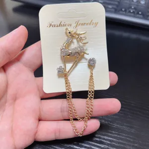 Close-up detail of rhinestone deer brooch with hanging chains sparkling crystals and metal alloy.