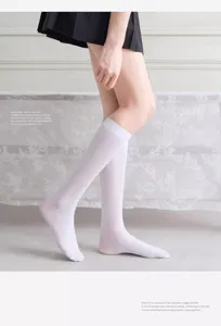 Detailed view of white velvet knee high socks worn by leg model in clean interior setting.