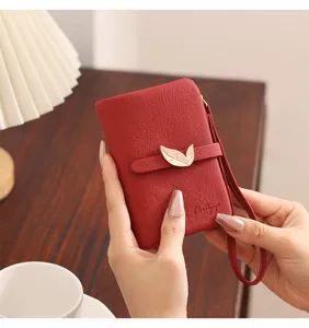 Women's short red wallet with elegant leaf metal clasp, zipper and wrist strap.
