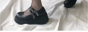 Scarpe Mary Jane con plateau in stile gotico abbinate a calze a rete nere alla moda.