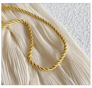 Detalle de correa de hombro torcida dorada, accesorio elegante y duradero para bolsos.