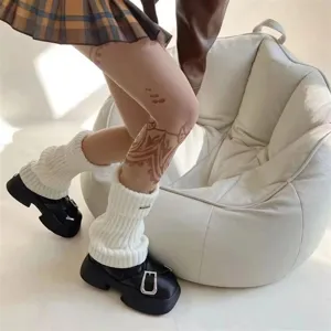 Detailaufnahme weißer Strick-Beinwärmer kombiniert mit schwarzen Plateau-Schuhen, Winter.