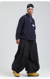 Detailed view of loose baggy ski pants paired with fleece pullover and boots.