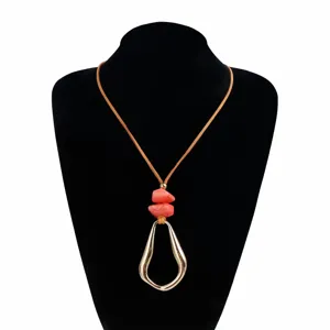 Detail shot of the irregular geometric pendant and coral bead necklace on black bust.