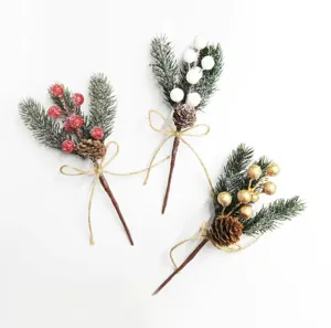 Künstliche Weihnachtskiefern Zweige mit Zapfen roten weißen goldenen Beeren und Jute Schleife.