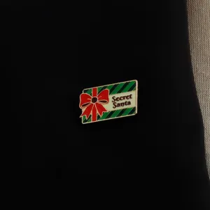 Κοντινή λήψη μιας όμορφης χριστουγεννιάτικης καρφίτσας σμάλτου κουτιού δώρου με φιόγκο.