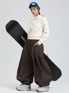 Women's loose wide leg waterproof windproof snowboarding pants with stylish white jacket outfit.