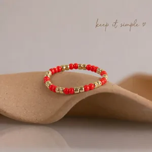 Red and gold beaded ring detail shot showcasing the vibrant color combination and delicate craftsmanship.