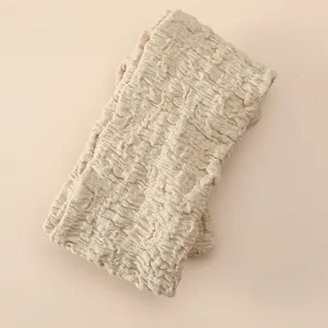 Vue détaillée du bandeau pour bébé en tissu froissé beige, montrant une texture douce et élastique.