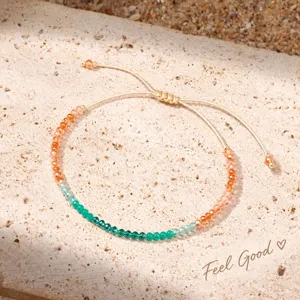 Close-up detail van verstelbare geweven armband met groene en oranje glazen kralen voor dames.