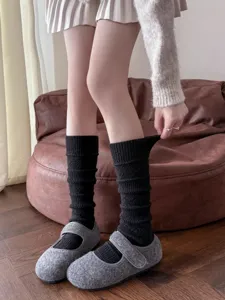 Dettaglio in primo piano di calze in maglia nera abbinate a scarpe di lana grigia.