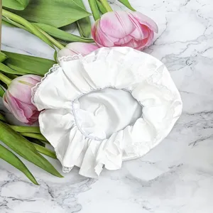 Détail en gros plan du bonnet de soubrette en dentelle blanche avec bordure froncée.