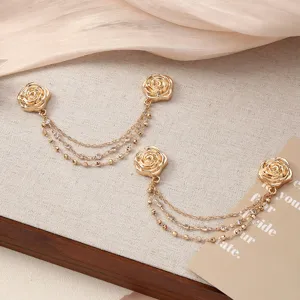 Close-up detail of golden rose magnetic clothing clip and crystal chain pants adjuster.