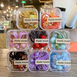 Boîtes d'élastiques à cheveux colorés pour enfants, bandeaux élastiques avec perles dans des étuis.