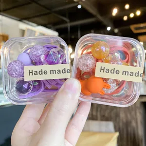 Vue détaillée d'élastiques à cheveux colorés en boîtes transparentes avec perles mignonnes.