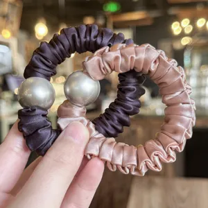 Detail shot of satin hair scrunchies with large metallic beads in elegant pink and dark brown.