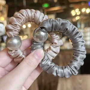 Detail view of satin hair scrunchie with shiny metal ball, soft elastic band for women.