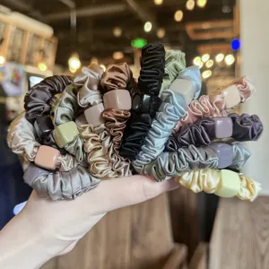 Gros plan détaillé de chouchous en satin multicolores avec perles carrées chics, élastiques.