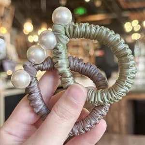 Vue détaillée de chouchous de cheveux en satin élégants avec de grandes perles.