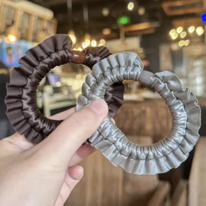 Vista dettagliata di eleganti elastici per capelli in raso arricciato marrone e argento.