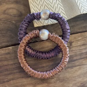 Gros plan détaillé de chouchous en satin avec perle, élastique élégant pour cheveux.