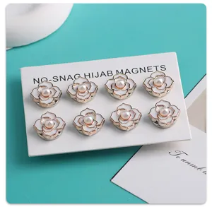 Detailopname van elegante witte bloemvormige hijab-magneetspelden met parel voor sjaal.